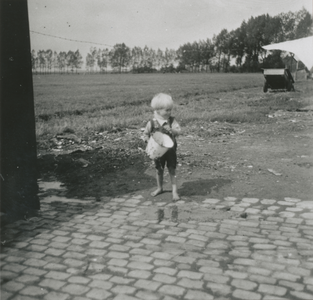 876867 Afbeelding van een jongetje dat blootsvoets is en een emmer in handen heeft, bij het woonwagenkamp aan de ...